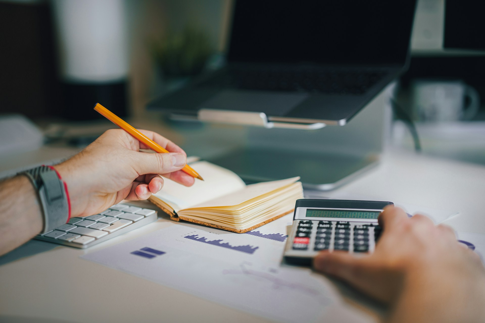 A person with pen, paper and pencil calculating his tax