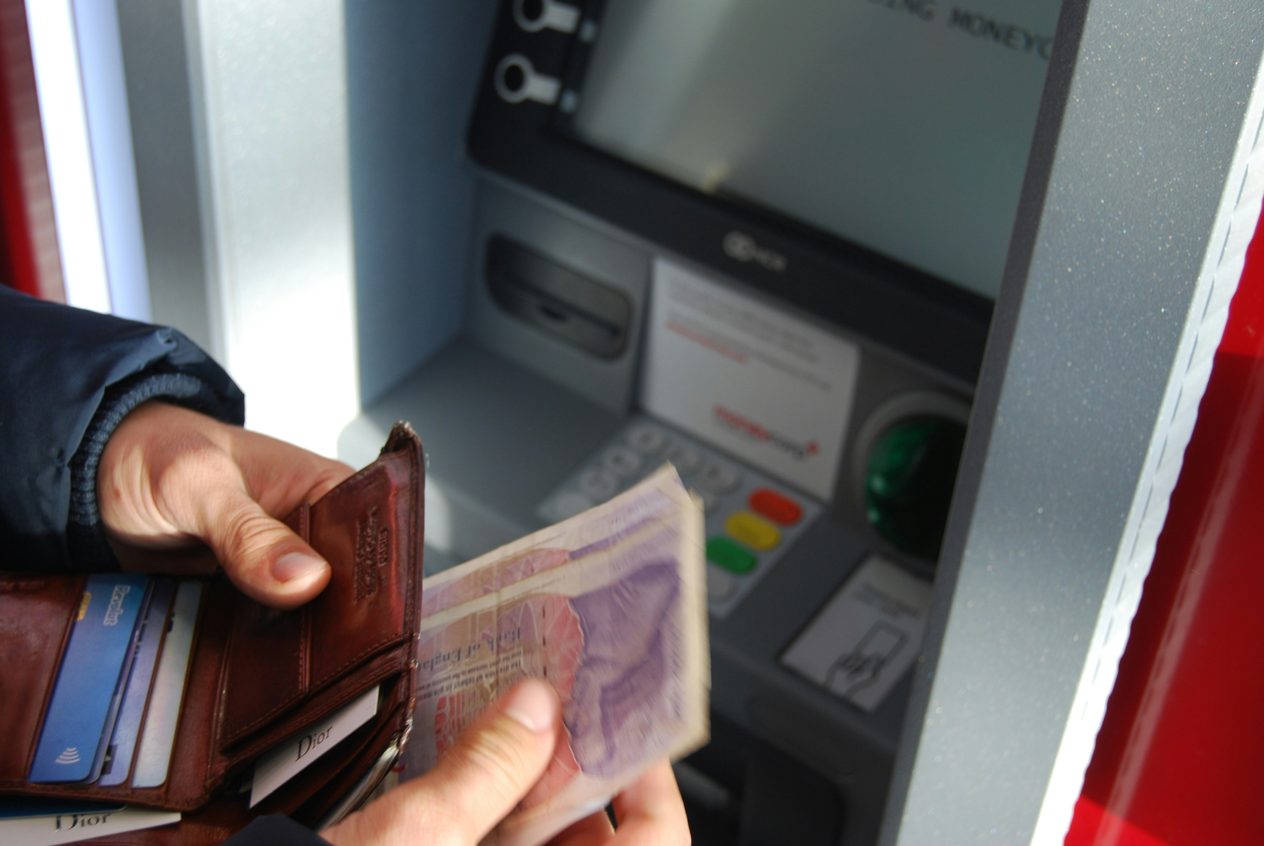 Person counting money near an ATM