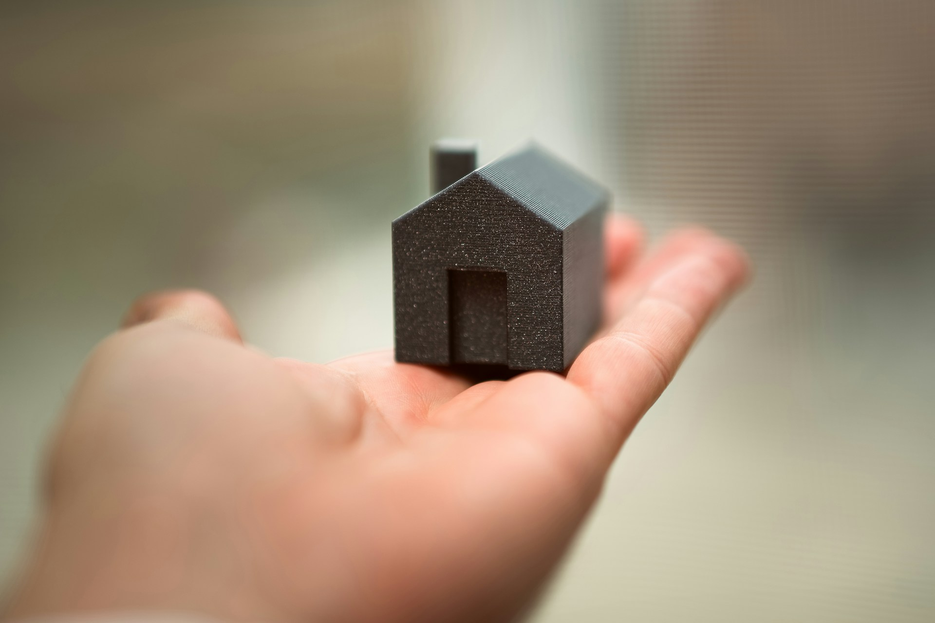 A hand holding a miniature house