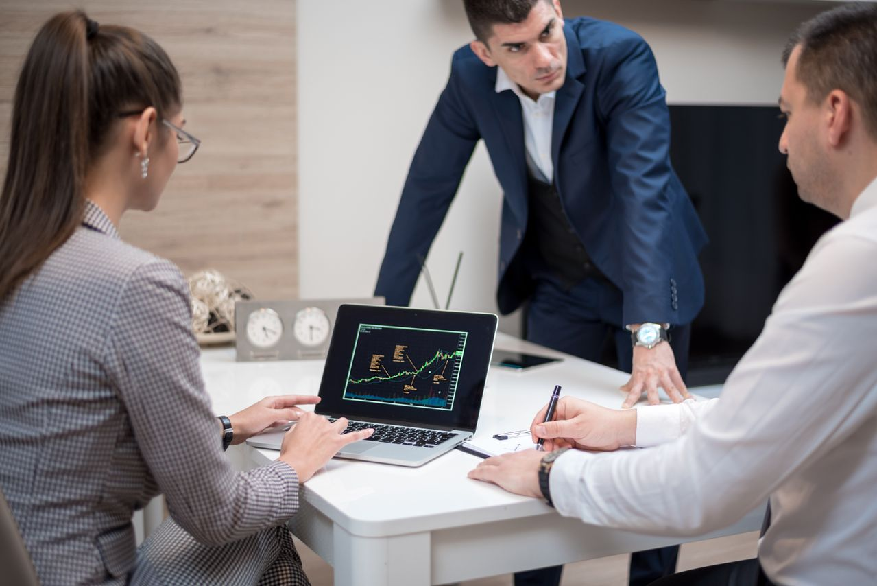 A group of people analyzing stock market trends on a laptop