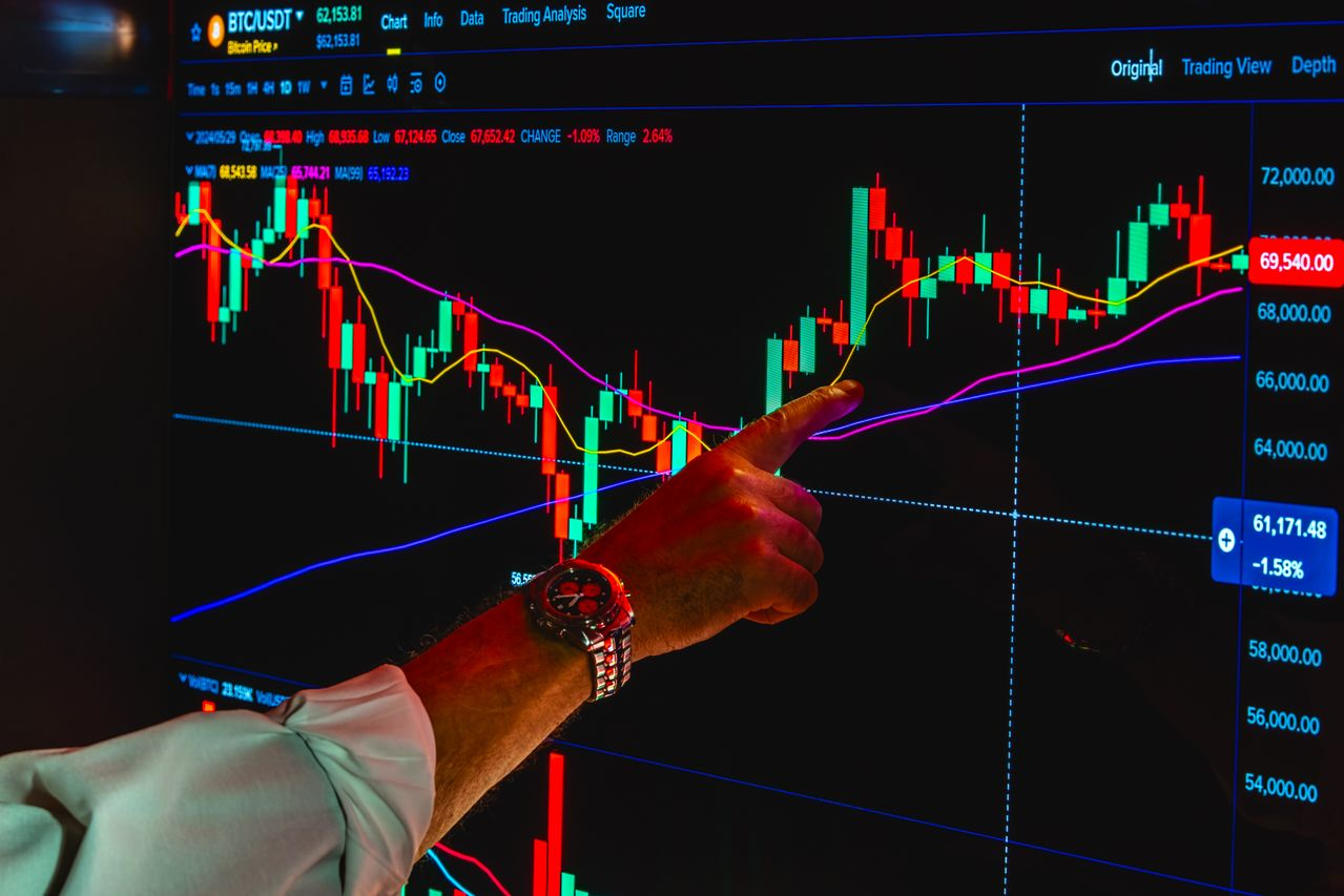 A hand pointing at a crypto market chart