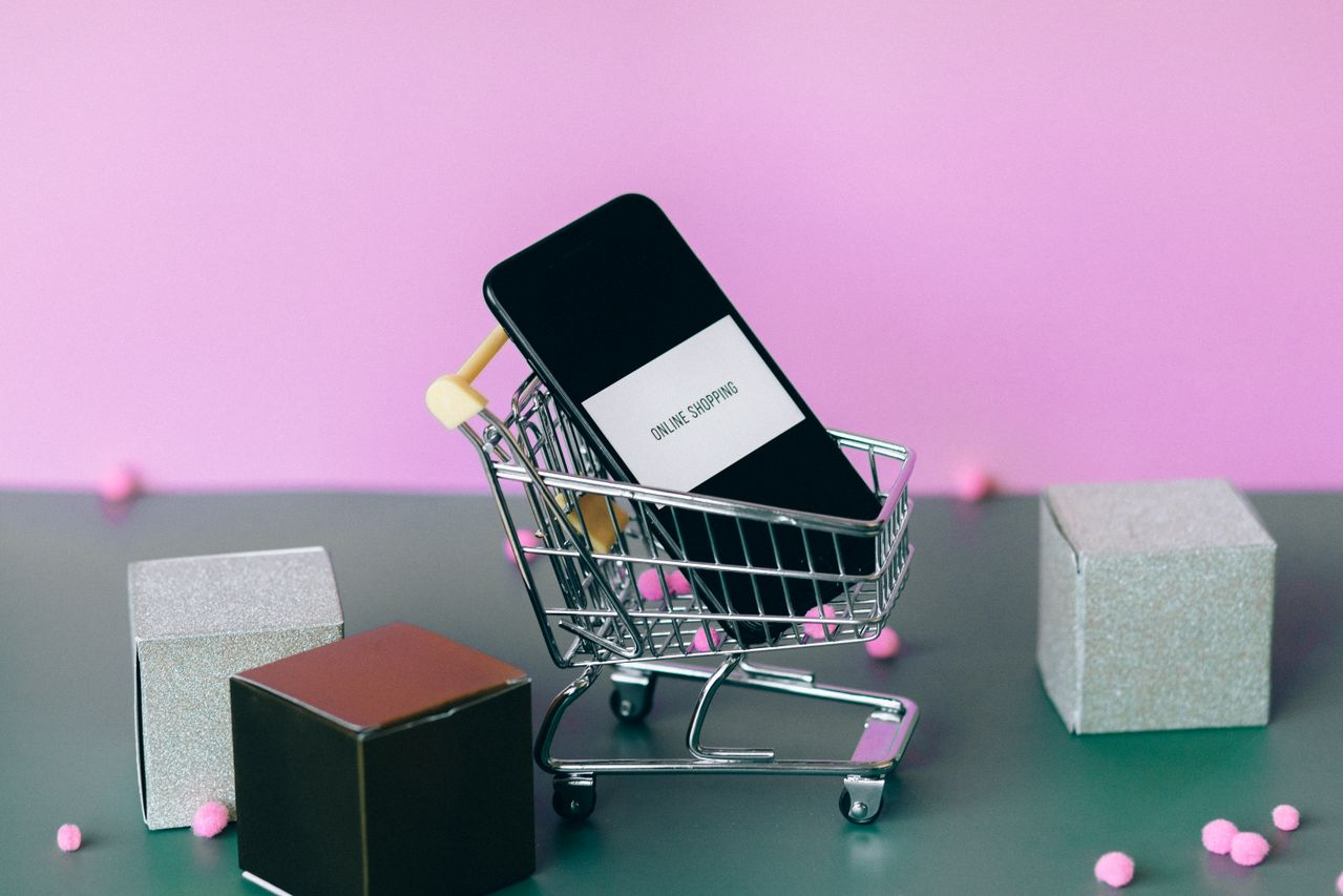 A phone with the text online shopping on a small cart