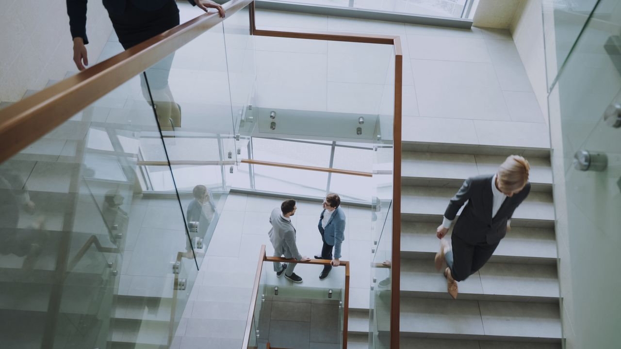 Aerial view of professionals conversing in a glass staircase