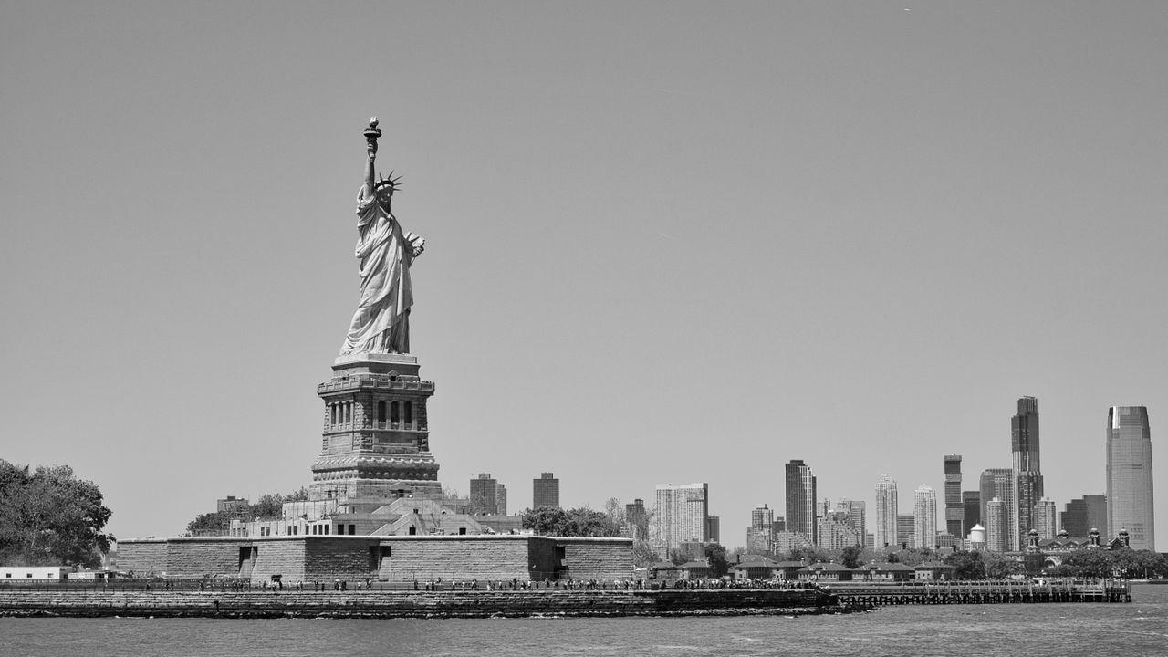 Black and white image of the Statue of Liberty with the New York City skyline