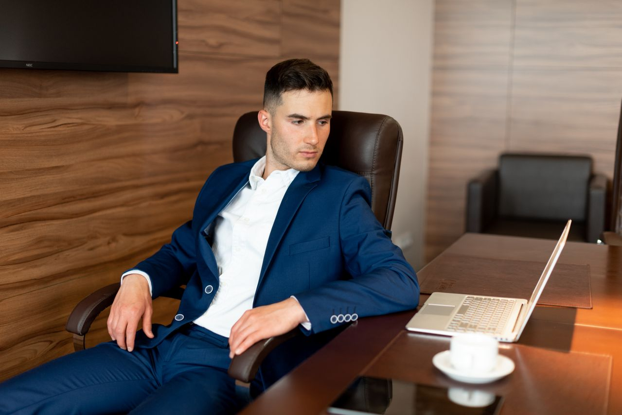 Businessman in blue suit seated at a desk with laptop