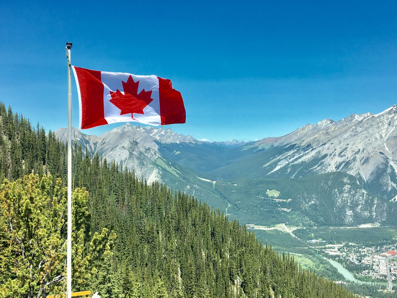 Canadian flag waving atop a scenic mountain view
