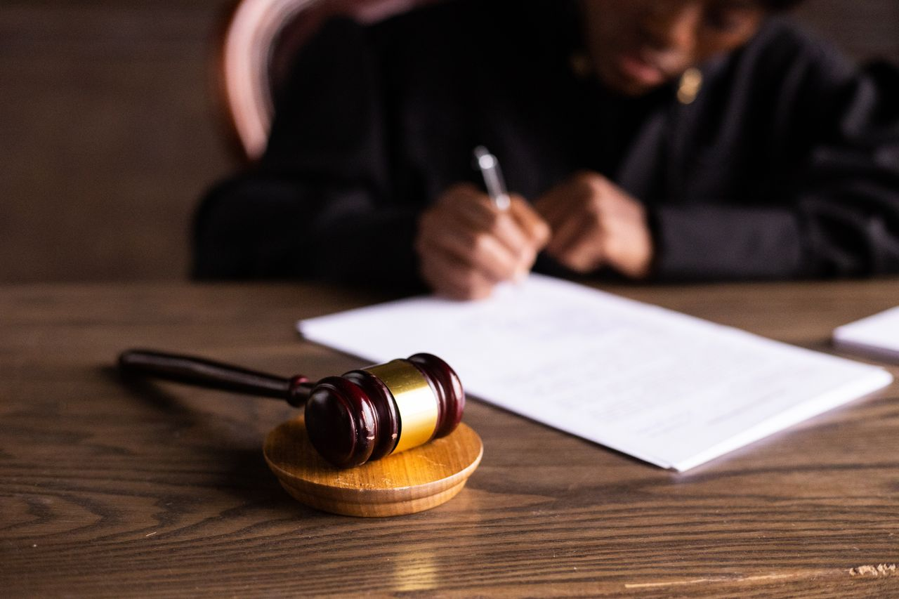 Judge signing documents at desk with focus on gavel