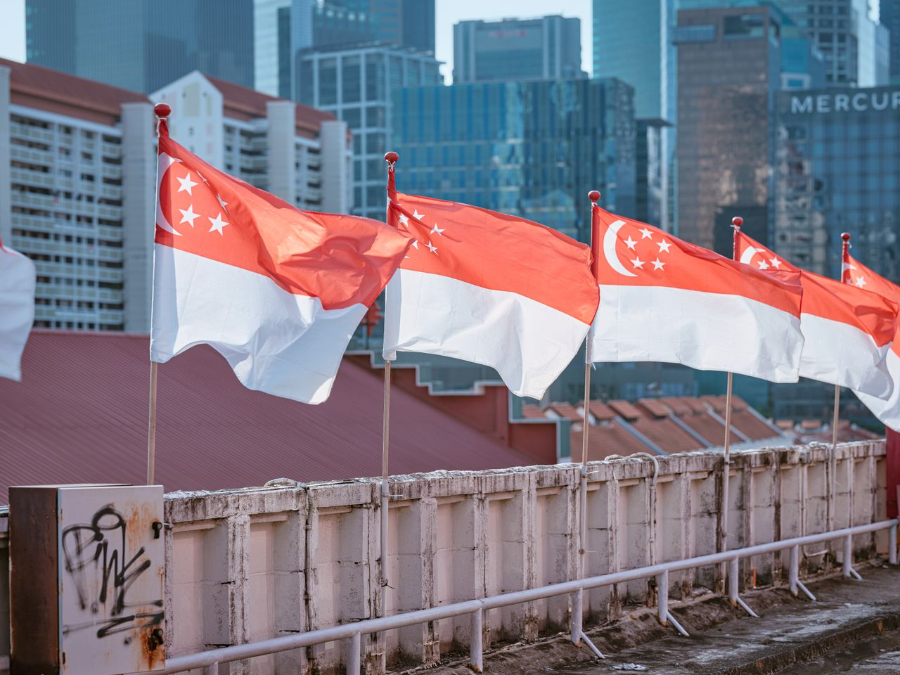 Singapore national flags waving in front of a modern urban skyline