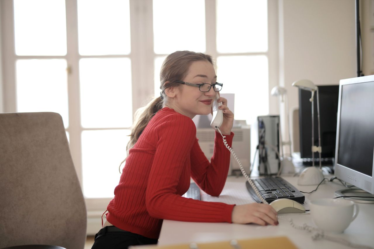 Woman in red sweater talking on landline phone